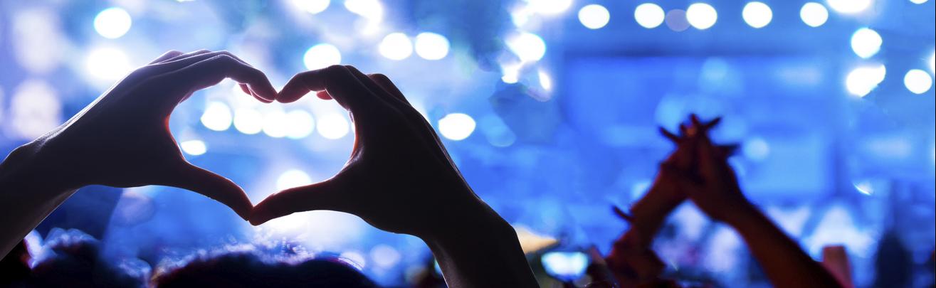 Audience members create hearts with their hands.